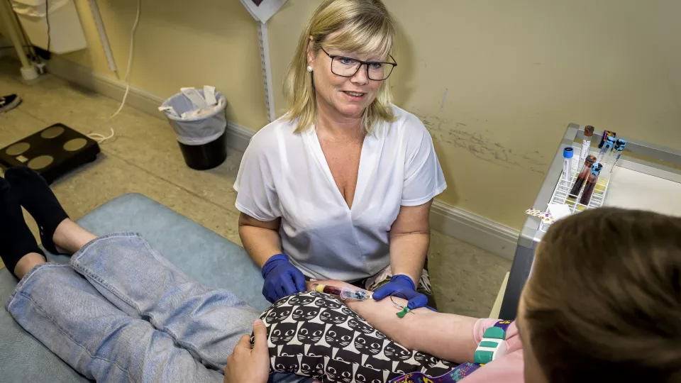 Foto på en forskningssjuksköterska som tar blodprov på ett barn.