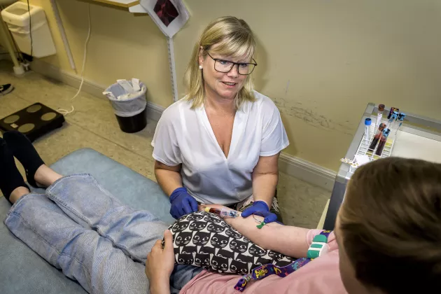Foto på en forskningssjuksköterska som tar blodprov på ett barn.