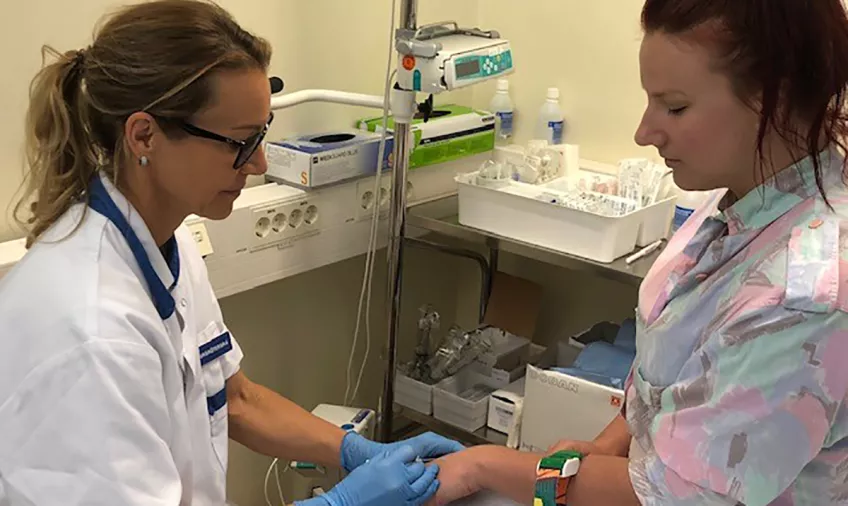 Bilden visar en sjuksköterska som tar blodprov på en patient